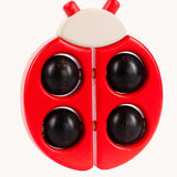 Bajo Red Ladybird Teether, a red coloured wooden teether toy with black coloured ball details. 