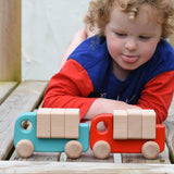 A child playing with a light blue and red Bajo trucks. 