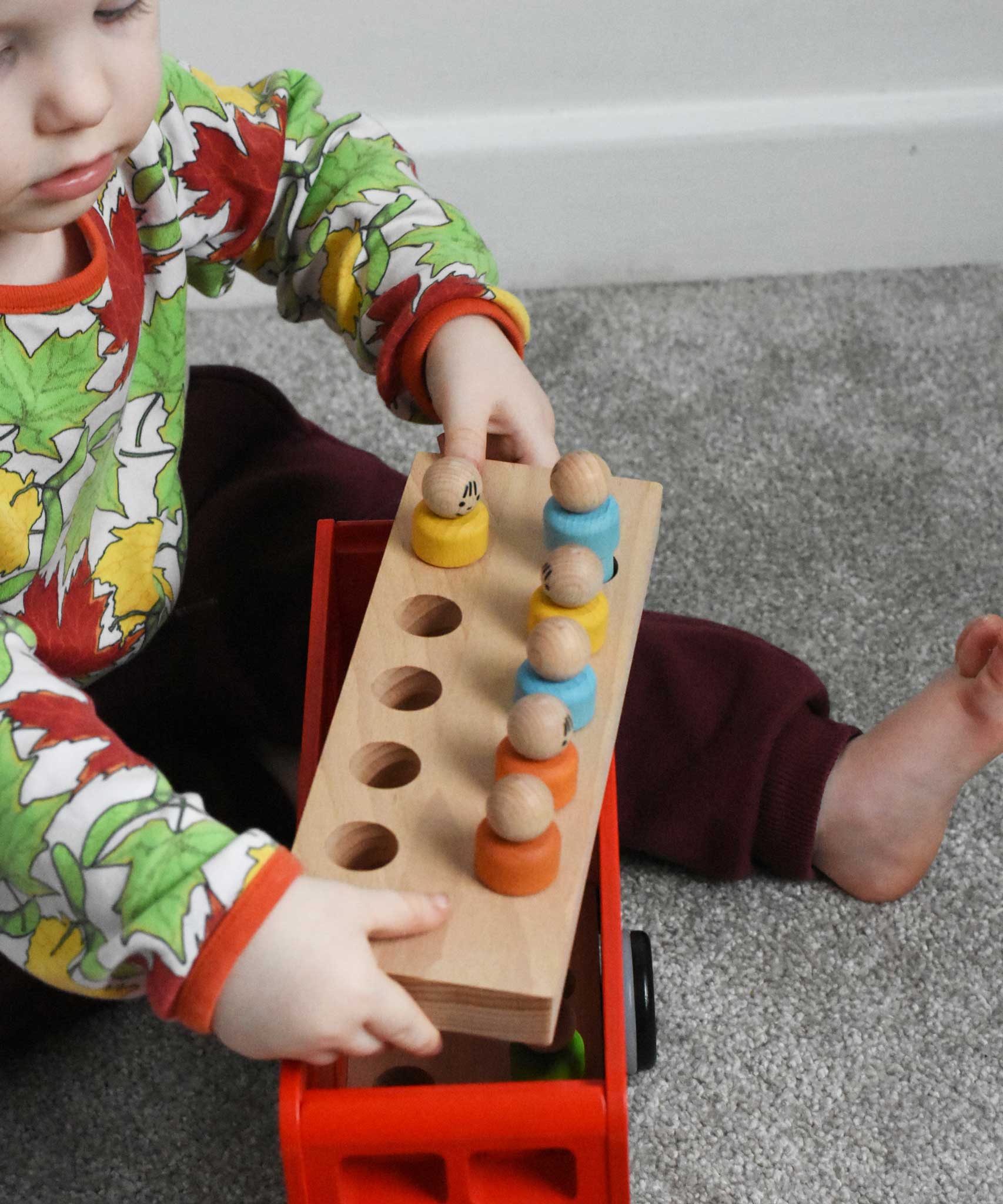 A child playing with the Bajo London bus wooden toy. The roof has been taken off and the child is lifting the middle floor of the bus full of wooden peg dolls out from the bus. These heirloom quality toys by Bajo are part of a wide range of wooden toys available here at Babipur. 