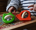 Bajo red snail rattle and green frog baby toys placed on a rattan stool.