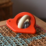 Bajo red snail rattle baby toy placed on a rattan stool.