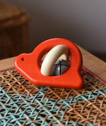 Bajo red snail rattle baby toy placed on a rattan stool.