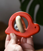 Bajo red snail rattle baby toy in an adult hand.