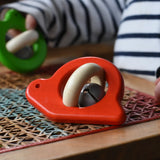 Bajo red snail rattle baby toy placed on a rattan stool.