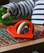 Bajo red snail rattle baby toy placed on a rattan stool.