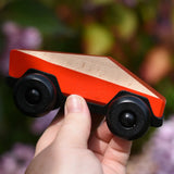 Bajo red ToBe Poly car wooden toy in an adult's hand.