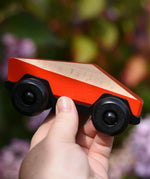 Bajo red ToBe Poly car wooden toy in an adult's hand.