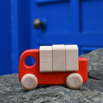 A red Bajo truck with blocks placed on a stone wall