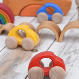 A group of Bajo handmade wooden beetle style car including blue, yellow and red available at Babipur. Cars have unpainted wheels and can be pulled or pushed along.