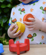 Child playing with teh Bajo stacking rocket wooden toy.