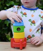 Child placing the top pieces on the Bajo stacking rocket wooden toy.