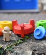 Bajo stacking rocket wooden toy red base piece placed on a stone wall wit the pieces besides it.