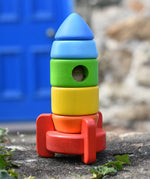Bajo stacking rocket wooden toy placed on a stone wall. 