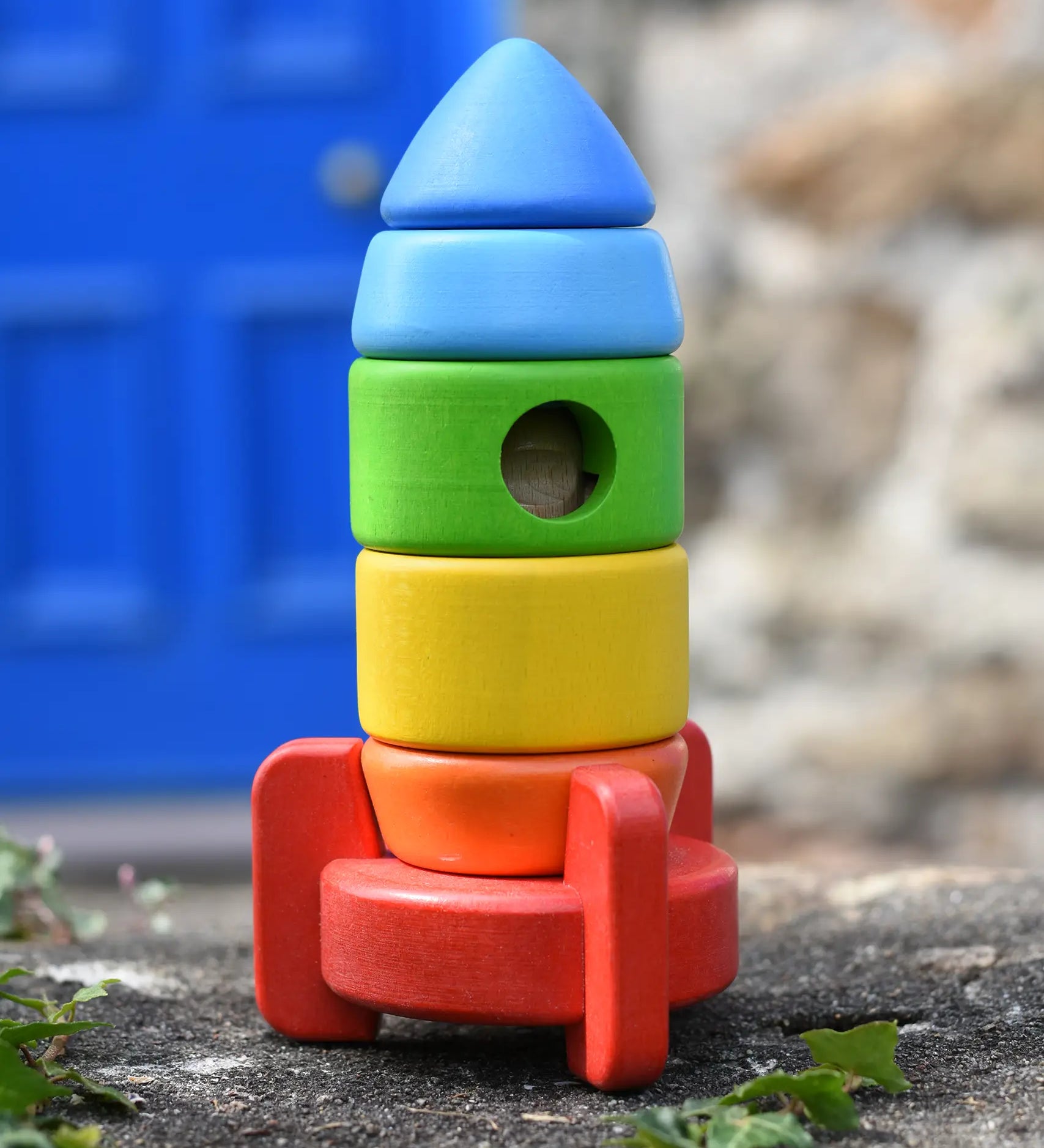 Bajo stacking rocket wooden toy placed on a stone wall. 