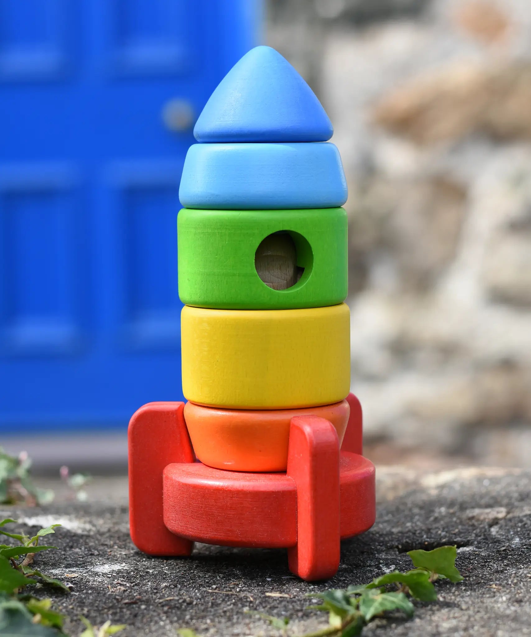 Bajo stacking rocket wooden toy placed on a stone wall. 
