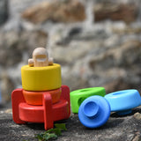 Bajo stacking rocket wooden toy placed on a stone wall, the top three pieces have been placed besides the base piece.
