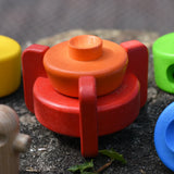 Two bottom pieces from the Bajo stacking rocket wooden toy placed on the stone wall