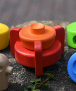 Two bottom pieces from the Bajo stacking rocket wooden toy placed on the stone wall