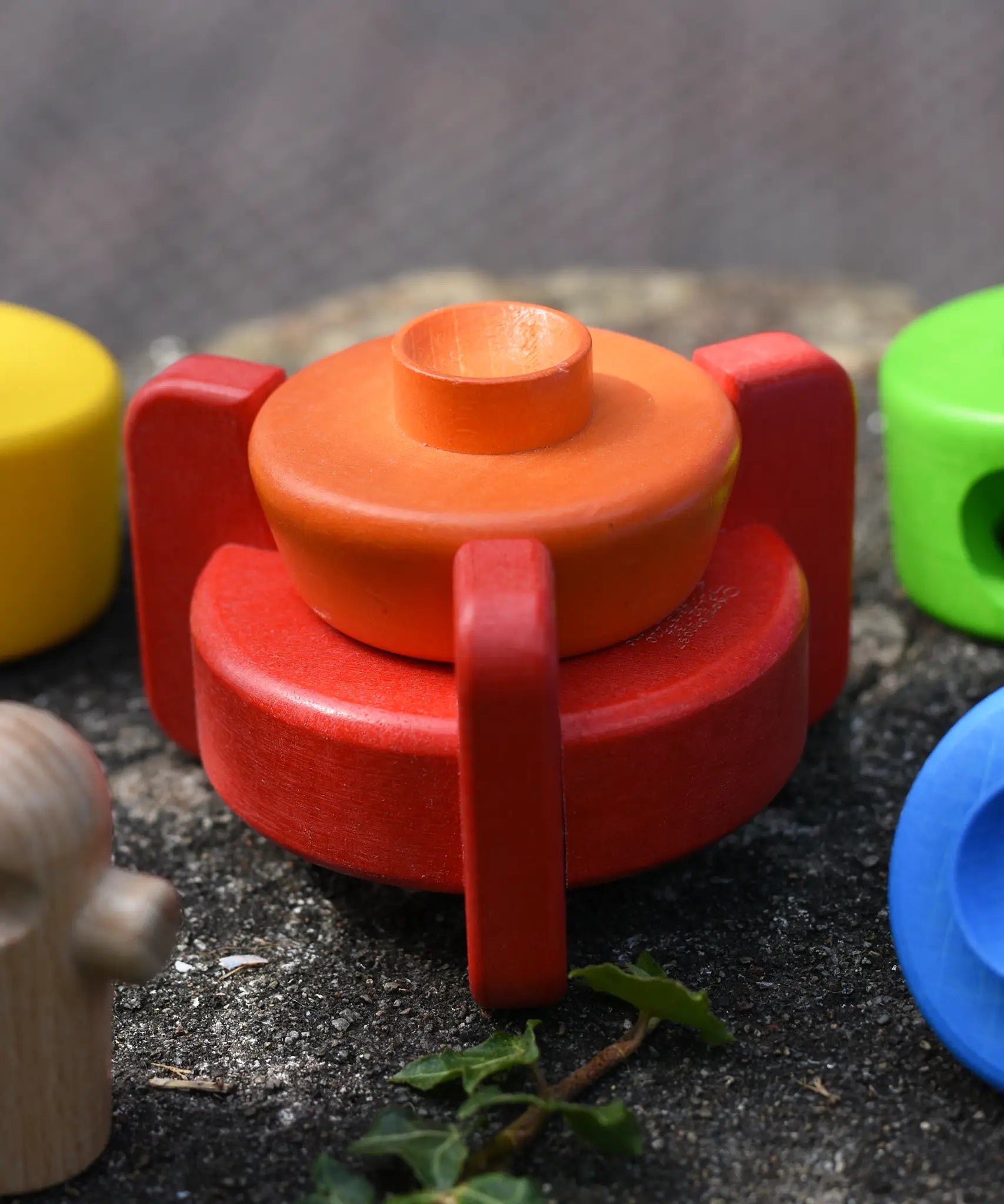 Two bottom pieces from the Bajo stacking rocket wooden toy placed on the stone wall