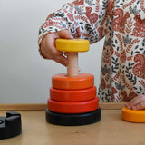 A child playing with a red coloured Bajo wooden rook stacking tower toy. There are little notches on the wooden stacking pole. These heirloom quality toys by Bajo are part of a wide range of wooden toys available here at Babipur.