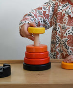 A child playing with a red coloured Bajo wooden rook stacking tower toy. There are little notches on the wooden stacking pole. These heirloom quality toys by Bajo are part of a wide range of wooden toys available here at Babipur.