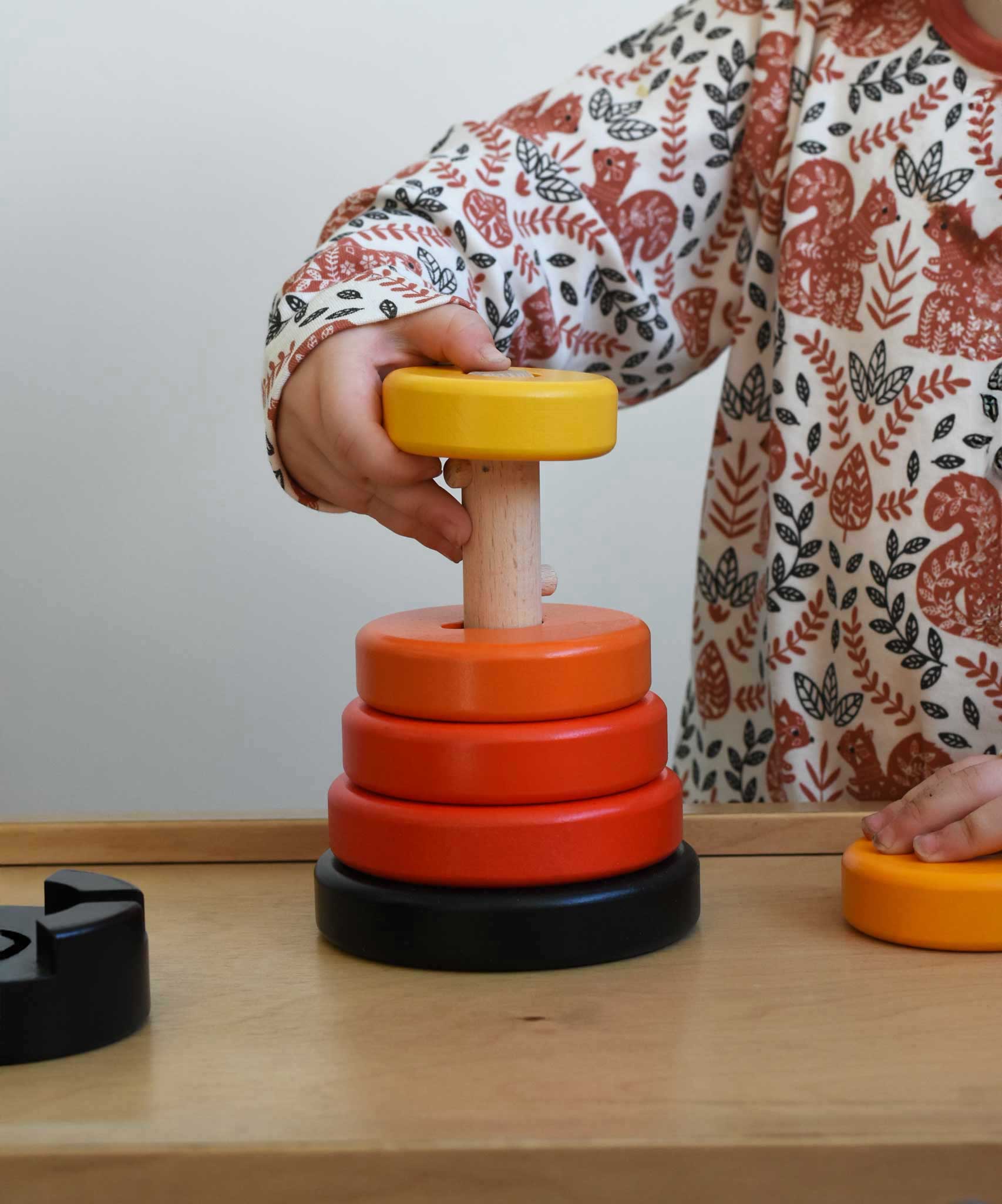 A child playing with a red coloured Bajo wooden rook stacking tower toy. There are little notches on the wooden stacking pole. These heirloom quality toys by Bajo are part of a wide range of wooden toys available here at Babipur.