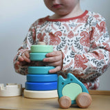 A child playing with a blue coloured Bajo wooden rook stacking tower toy. A Bajo ghost toy has been placed in front of it. These heirloom quality toys by Bajo are part of a wide range of wooden toys available here at Babipur.