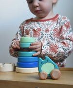 A child playing with a blue coloured Bajo wooden rook stacking tower toy. A Bajo ghost toy has been placed in front of it. These heirloom quality toys by Bajo are part of a wide range of wooden toys available here at Babipur.