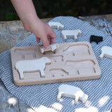 Child placing pieces into the shaped slots of the Bajo sheep puzzle base. 