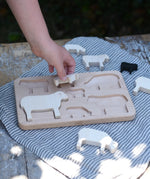 Child placing pieces into the shaped slots of the Bajo sheep puzzle base. 