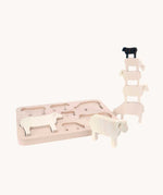 Bajo Sheep Puzzle. A wooden frame with 7 sheep shaped figures. Some of the figures are placed in the frame with others placed in a stack by the side of the frame.