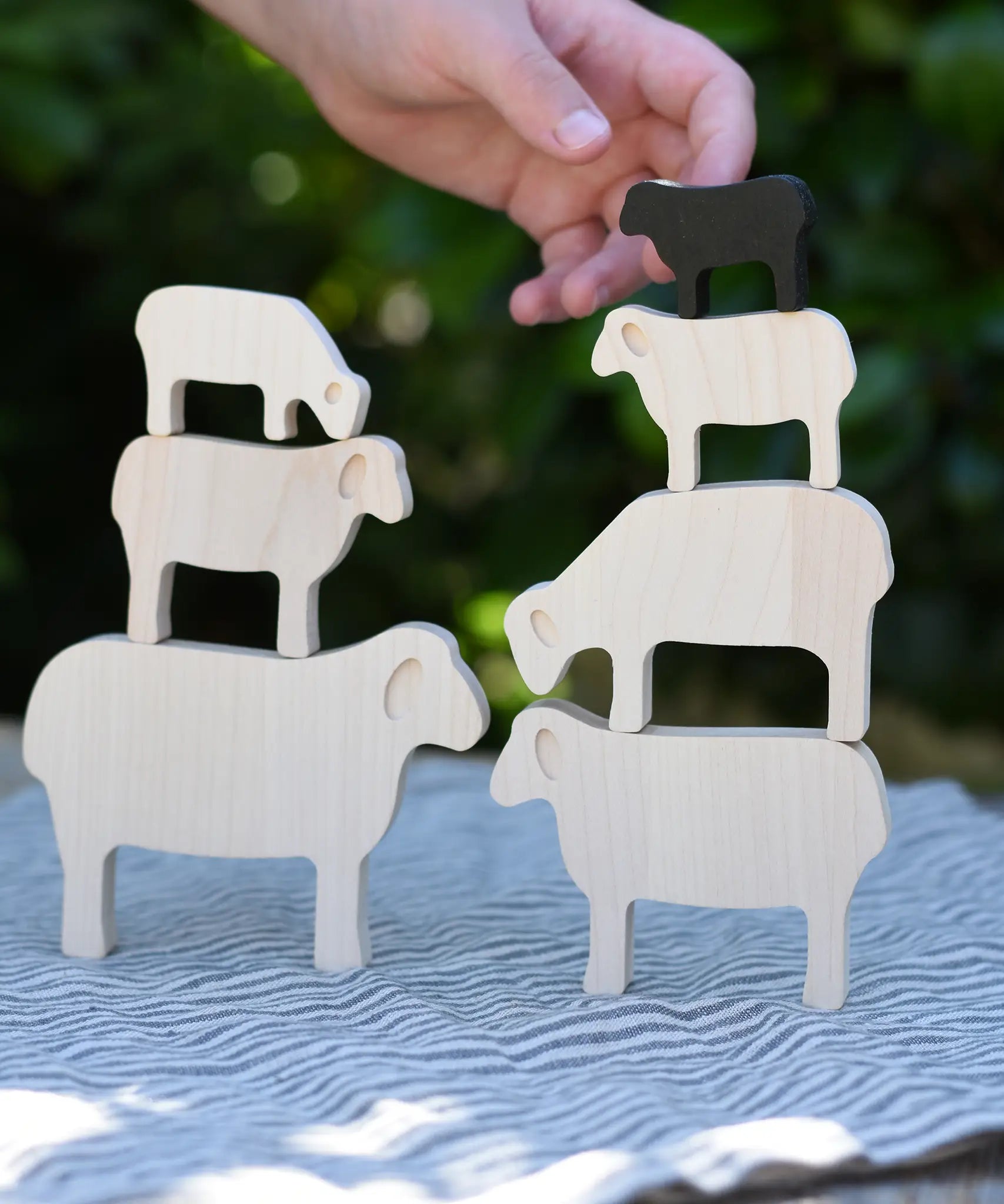 Child stacking the figures from the Bajo sheep puzzle on top of each other.