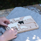 Child placing the figures from the Bajo sheep puzzle on the base frame.