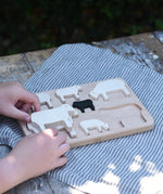 Child placing the figures from the Bajo sheep puzzle on the base frame.