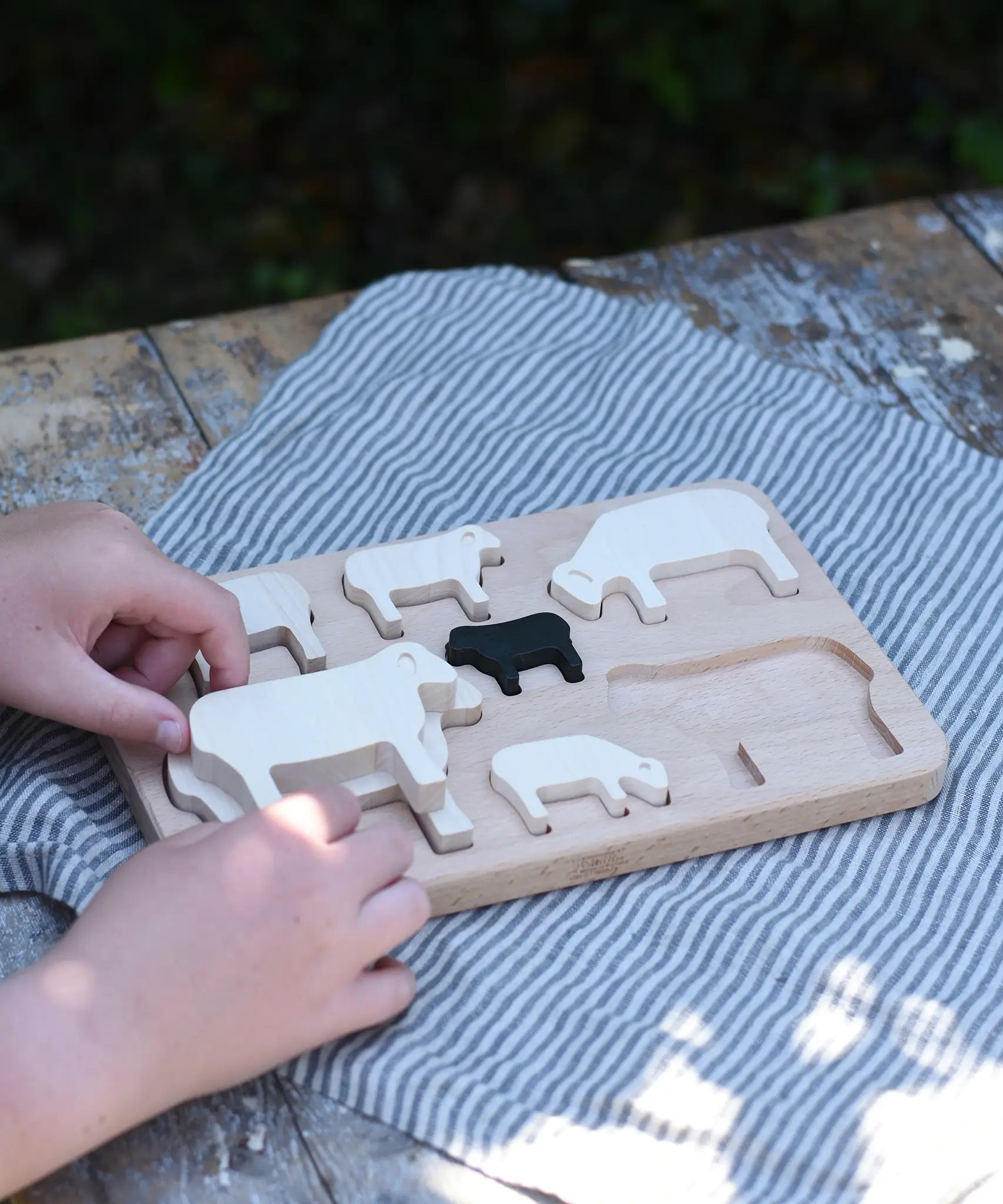 Child placing the figures from the Bajo sheep puzzle on the base frame.