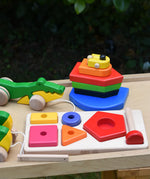 Bajo wooden toys placed on a wooden surface, nemo boat stacker toy, pyramid sorting board and crocodile pull along.
