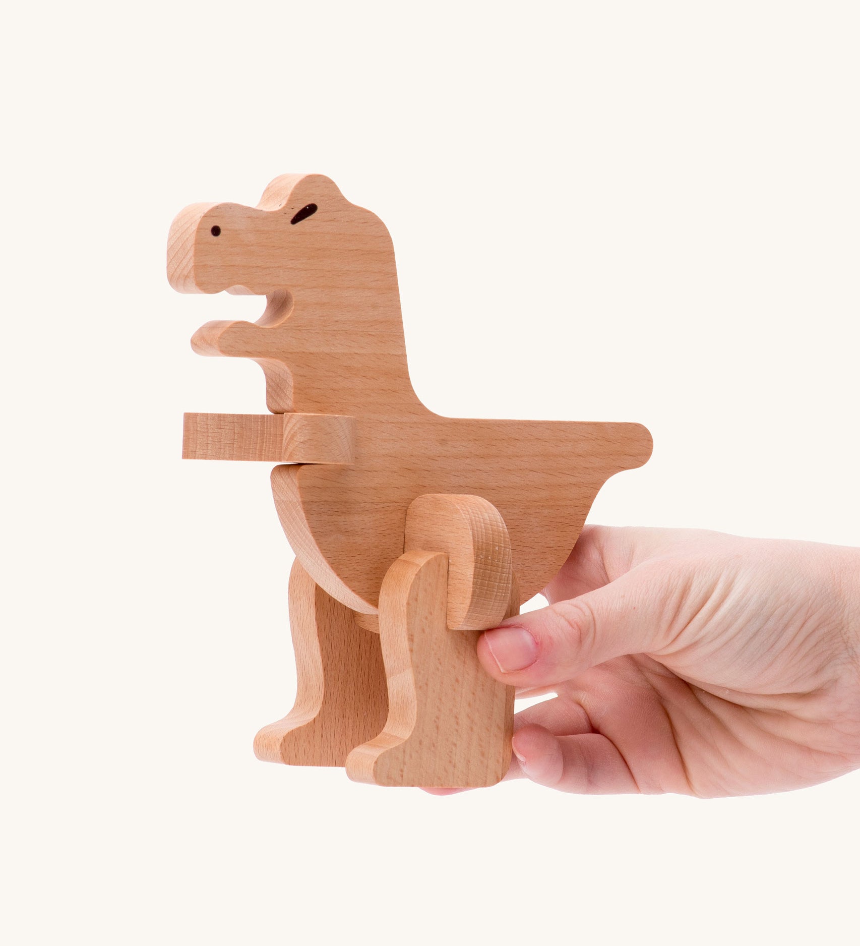 Bajo t-rex dinosaur wooden puzzle and sorter toy. The dinosaur shown in an adult's hand. These heirloom quality toys by Bajo are part of a wide range of wooden toys available here at Babipur. 