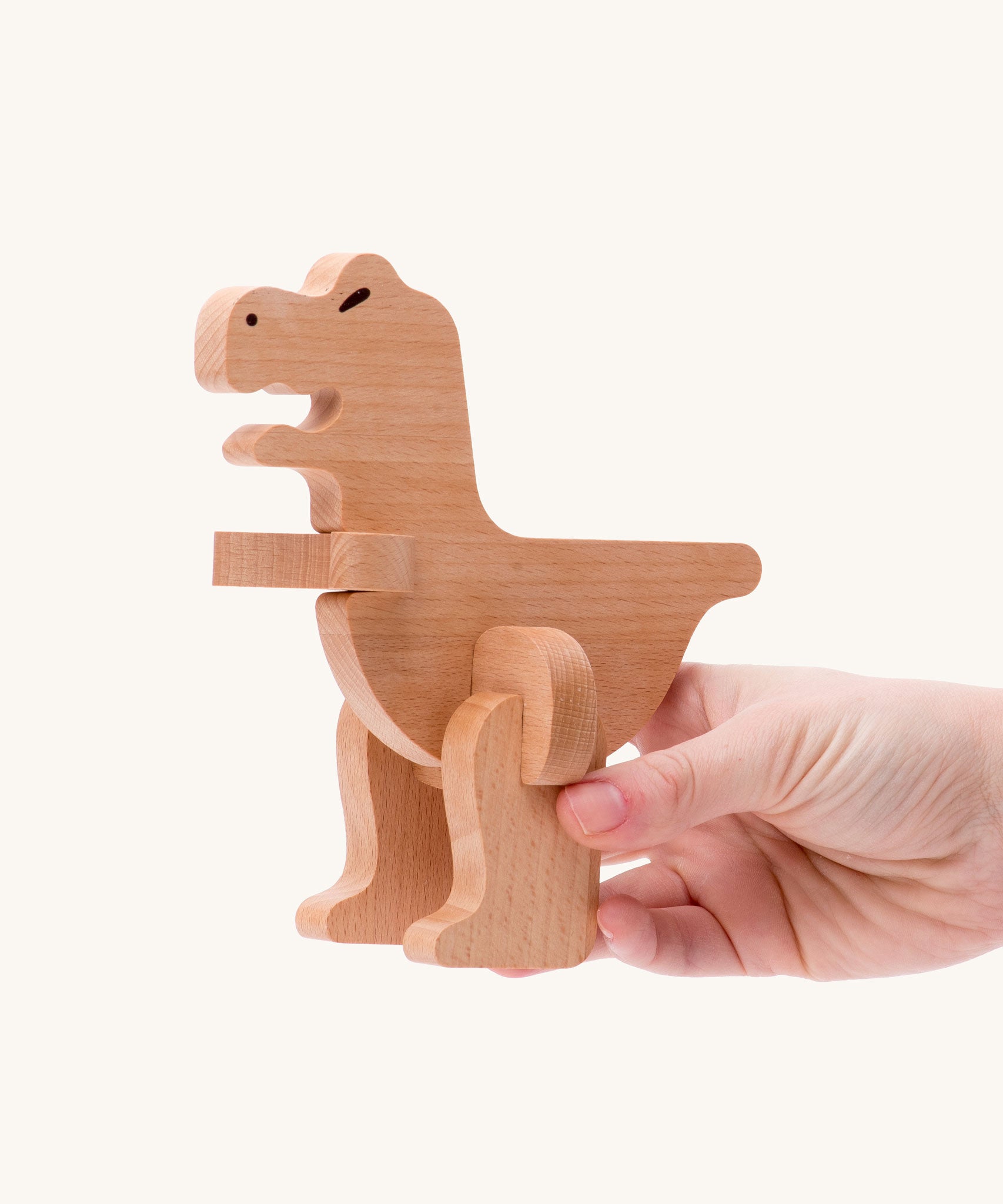 Bajo t-rex dinosaur wooden puzzle and sorter toy. The dinosaur shown in an adult's hand. These heirloom quality toys by Bajo are part of a wide range of wooden toys available here at Babipur. 
