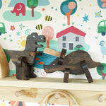 Bajo Puzzle & Sorter - Black Oak T-Rex and Triceratops on a wooden shelf with a colourful background
