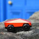Bajo red ToBe Poly car wooden toy on a stone wall.