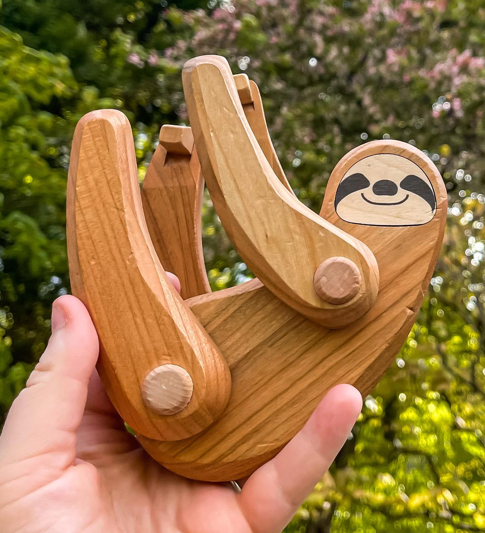 Close up of a hand holding the Bajo Tobe plastic-free sloth figure