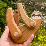 Close up of a hand holding the Bajo Tobe plastic-free sloth figure