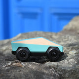 Bajo blue ToBe Poly car wooden toy on a stone wall.