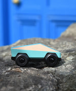 Bajo blue ToBe Poly car wooden toy on a stone wall.