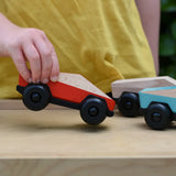 Bajo red ToBe Poly car wooden toy in a child's hand.