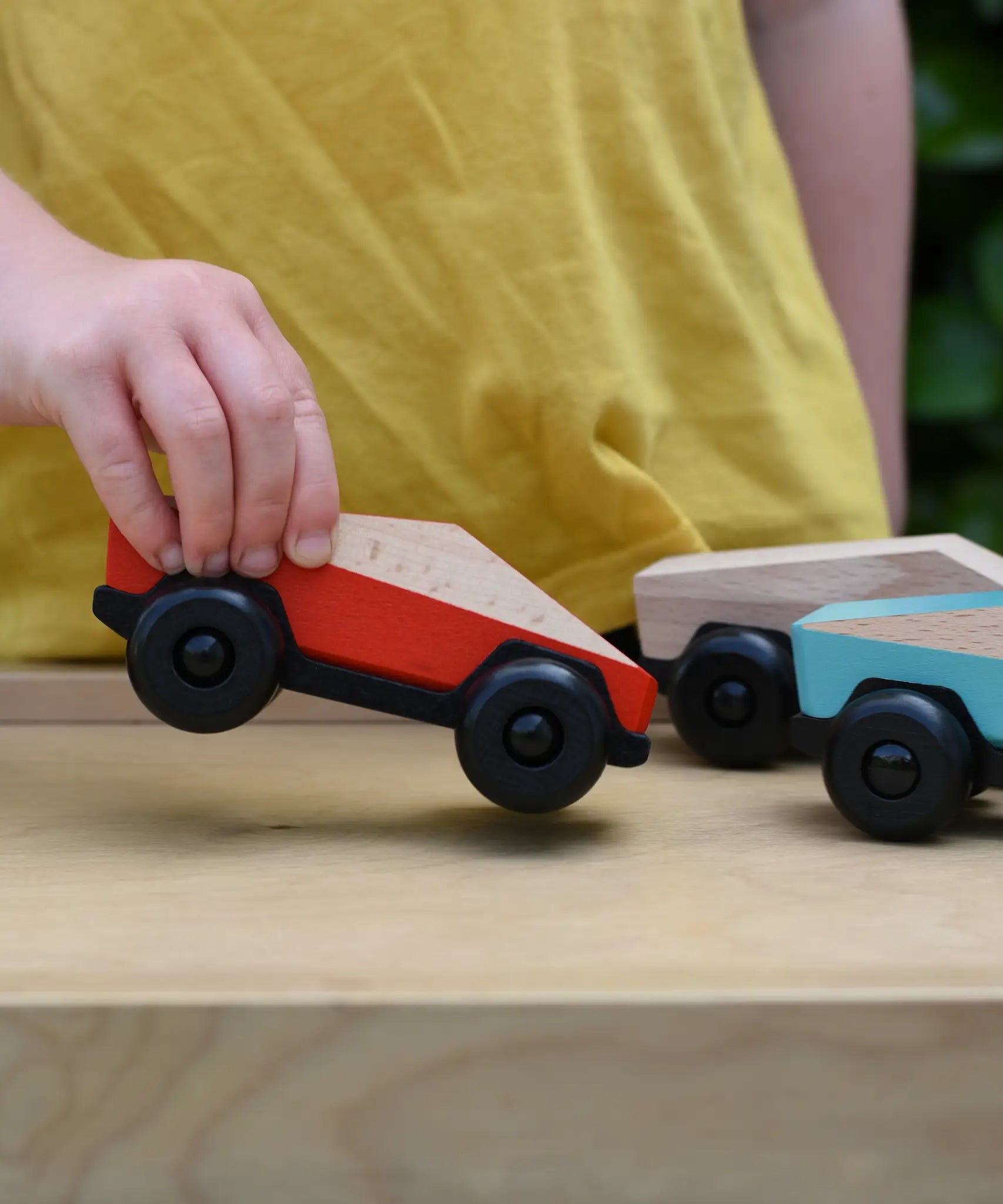 Bajo red ToBe Poly car wooden toy in a child's hand.