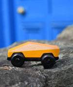 Bajo yellow ToBe Poly car wooden toy on a stone wall.