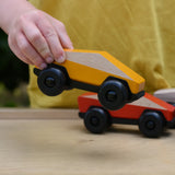 Bajo yellow ToBe Poly car wooden toy in a child's hand.