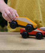 Bajo yellow ToBe Poly car wooden toy in a child's hand.