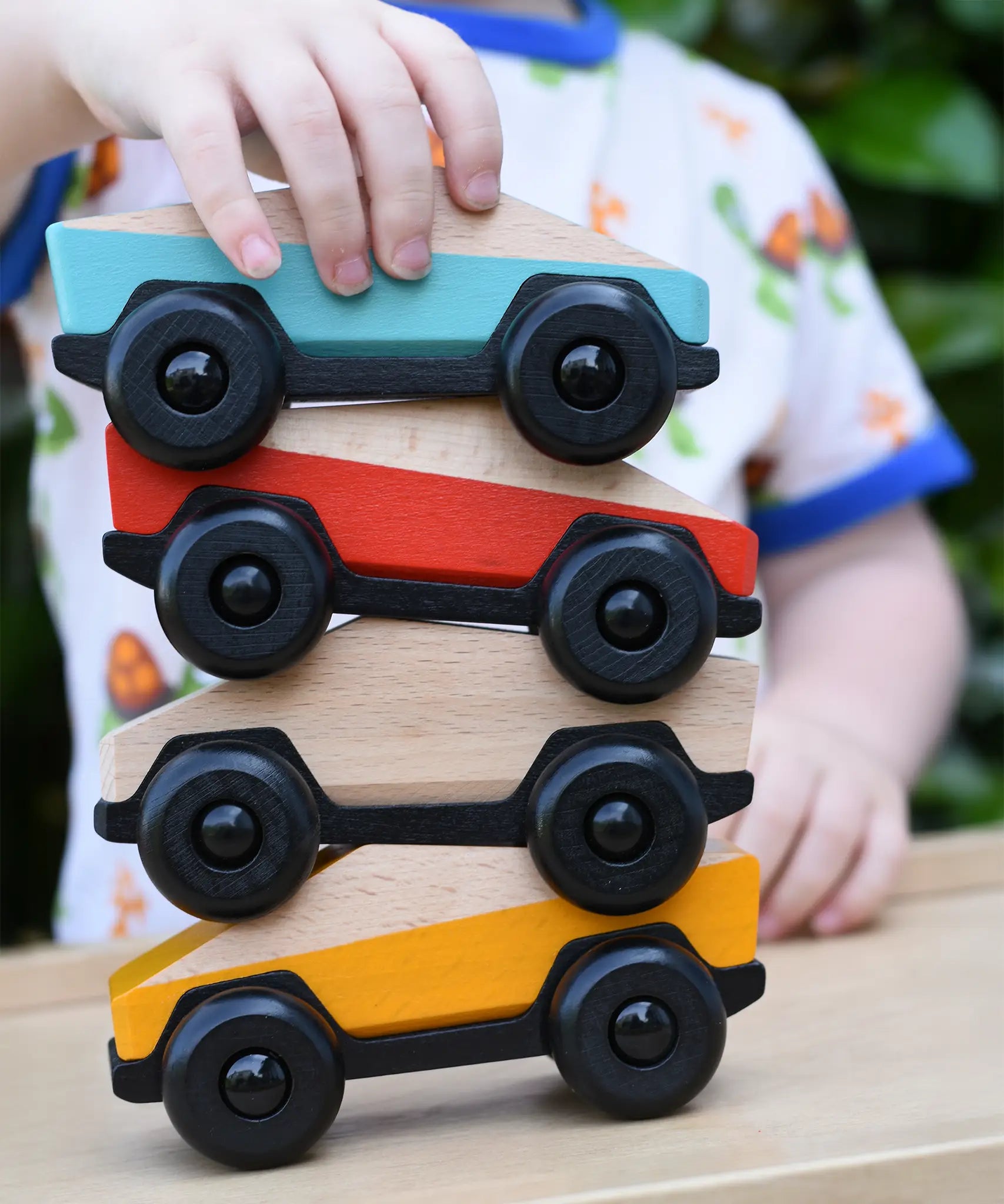 Four Bajo ToBe Poly cars wooden toys stacked up on top of each other.